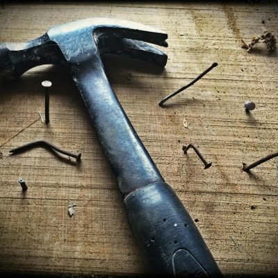 pexels photo 209235 209235 A weathered hammer surrounded by bent nails on a wooden plank, capturing the essence of carpentry work.