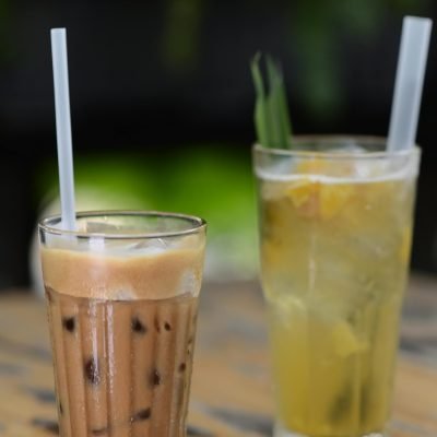 pexels photo 32612250 32612250 Close-up of iced coffee and herbal tea in glasses with straws on a wooden table, perfect for summer.